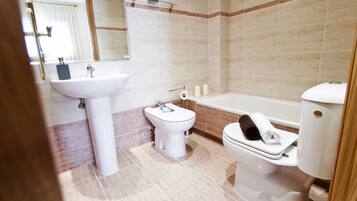 Une salle de bain équipée d’un lavabo, de toilettes, d’un bidet et d’une baignoire.