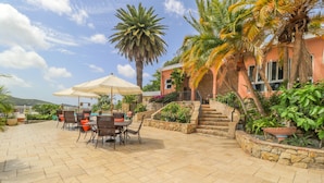 A patio with outdoor seating, a staircase, and a building with a stone facade.
