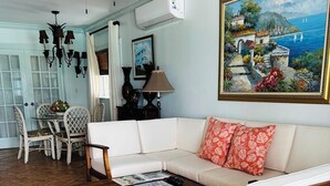 A living room with a white sofa, wooden coffee table, and a ceiling fan. - Henry Louise & The Parrot (Moss Town)