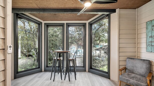 Une pièce d’angle avec de grandes fenêtres, un plafond en bois et un tabouret de bar.