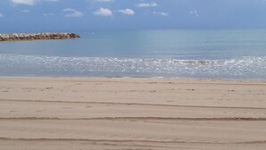 Une plage avec une digue rocheuse et des eaux calmes.