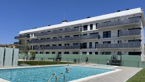 Un bâtiment moderne doté d’une piscine, de plusieurs balcons et d’un espace pelouse verdoyant.