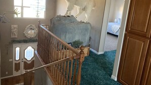 A room with a large rock sculpture on a staircase, a bed in the background, and a window with natural light. - Nice secluded home with plenty of room to roam! (Kanab)