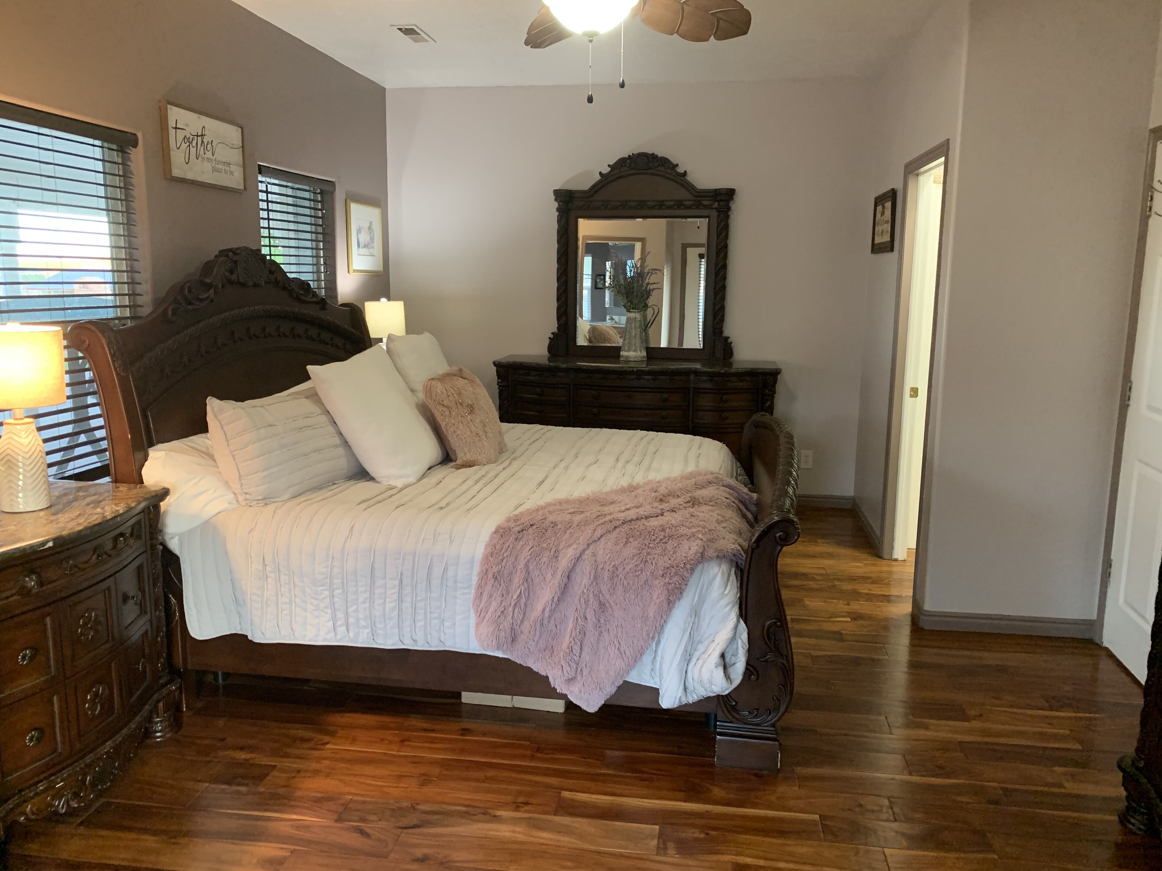 A bedroom with a large bed, wooden dresser, and a mirror.