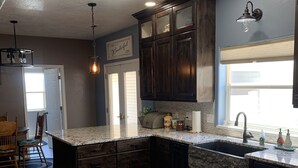 A kitchen with dark wooden cabinets, a granite countertop, a built-in sink, and a window with a view. - Nice secluded home with plenty of room to roam! (Kanab)