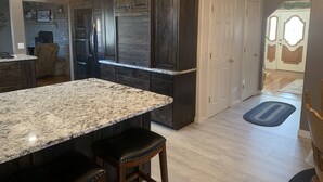 A kitchen with dark wood cabinets, a granite countertop, and a bar stool. - Nice secluded home with plenty of room to roam! (Kanab)