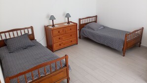 Une chambre avec deux lits en bois, une commode en bois et une table de chevet avec des lampes.
