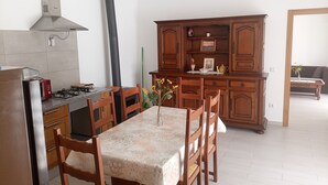 Une cuisine équipée d’une cuisinière à gaz, de meubles de rangement en bois et d’une table à manger avec des chaises.
