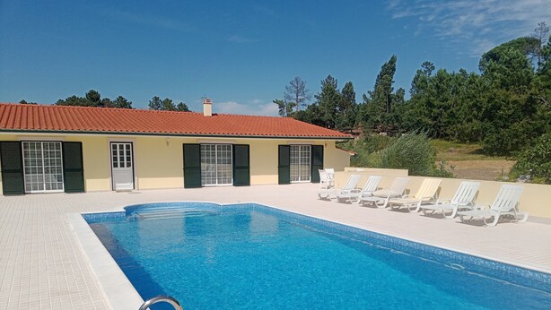 Une piscine dotée d’une terrasse carrelée, d’une échelle et de chaises longues.