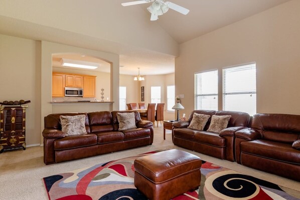 A spacious living room with two leather sofas, a coffee table, and a patterned rug.