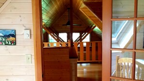 A wooden interior with a high ceiling, a wooden staircase, and a view through a glass door. - The "Belknap Cabin" (Blue River)