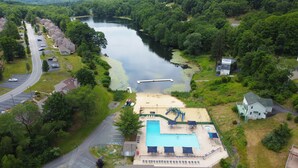 An aerial view of a residential area with a swimming pool, a dock, and a road. - Hot Tub, Pool, Game Room and more fun for the whole family (East Stroudsburg)