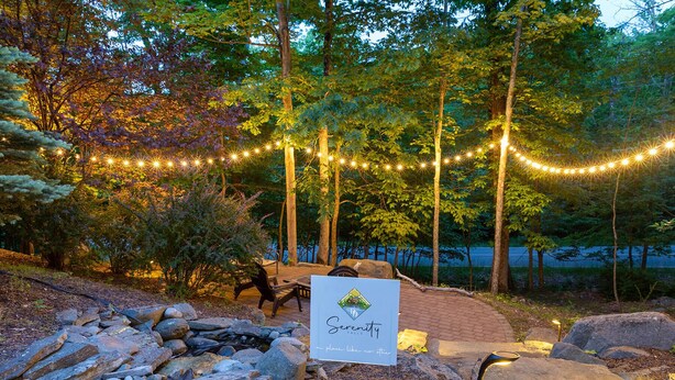 A serene outdoor setting with a stone pathway, a bench, and a sign that reads "Serenity Falls." - Hot Tub, Pool, Game Room and more fun for the whole family (East Stroudsburg)