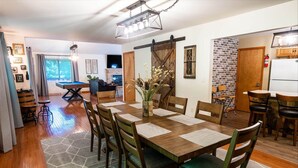 A dining area with a wooden table and chairs, a fireplace, and a brick wall. - Hot Tub, Pool, Game Room and more fun for the whole family (East Stroudsburg)