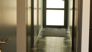 Un couloir doté d’un sol à motifs géométriques, d’une grande fenêtre et d’un luminaire suspendu.