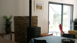 Un coin repas agrémenté d’une cheminée en pierre, d’une table avec des chaises et offrant une vue sur l’extérieur.