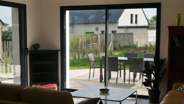 Un salon comprenant un canapé, une table basse et donnant sur une terrasse extérieure avec une table et des chaises.
