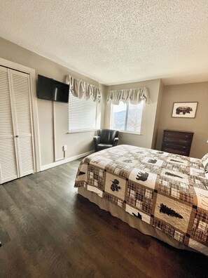 A bedroom with a bed, a chair, a TV, and a fireplace. - Smoky Mountain Memories: Stunning Mountain Views (Gatlinburg)