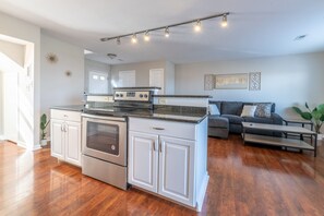 Enjoy cooking in the well-equipped kitchen with stainless steel appliances and an island, then relax in the adjacent living area with a comfortable sofa and bench.