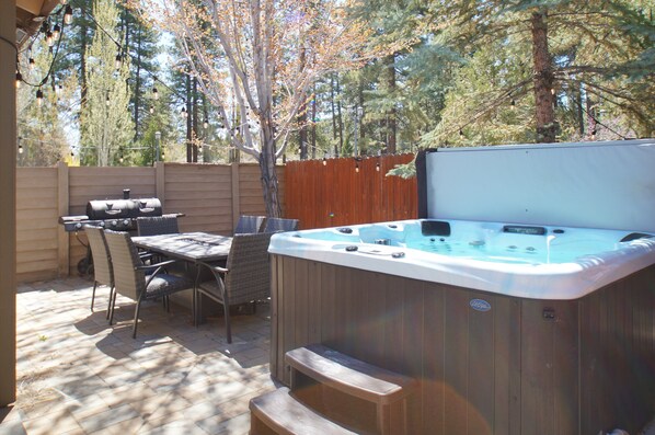 Un patio trasero con un jacuzzi, una parrilla y mobiliario exterior.