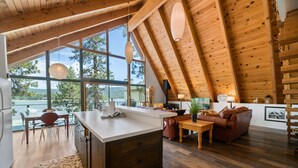 Una cocina amplia con una isla grande, techo de madera y ventanas grandes que ofrecen vistas al exterior.