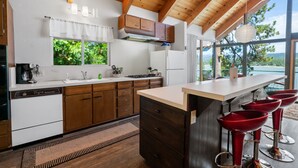 Una cocina moderna con armarios de madera, un refrigerador blanco y un amplio ventanal con vistas panorámicas.