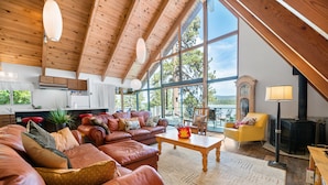 Amplia sala de estar con sofás de cuero, una mesa de centro de madera y ventanas grandes que ofrecen vistas al exterior.