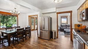 A modern kitchen with a stainless steel refrigerator, wooden dining table, and chairs.