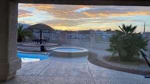 Dachpool-Bereich mit Blick auf einen Sonnenuntergang über einer Stadtlandschaft.
