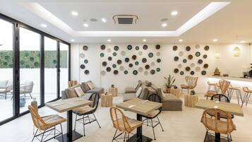 A modern dining area with tables and chairs, a wall decorated with plates, and a view of the outdoors.