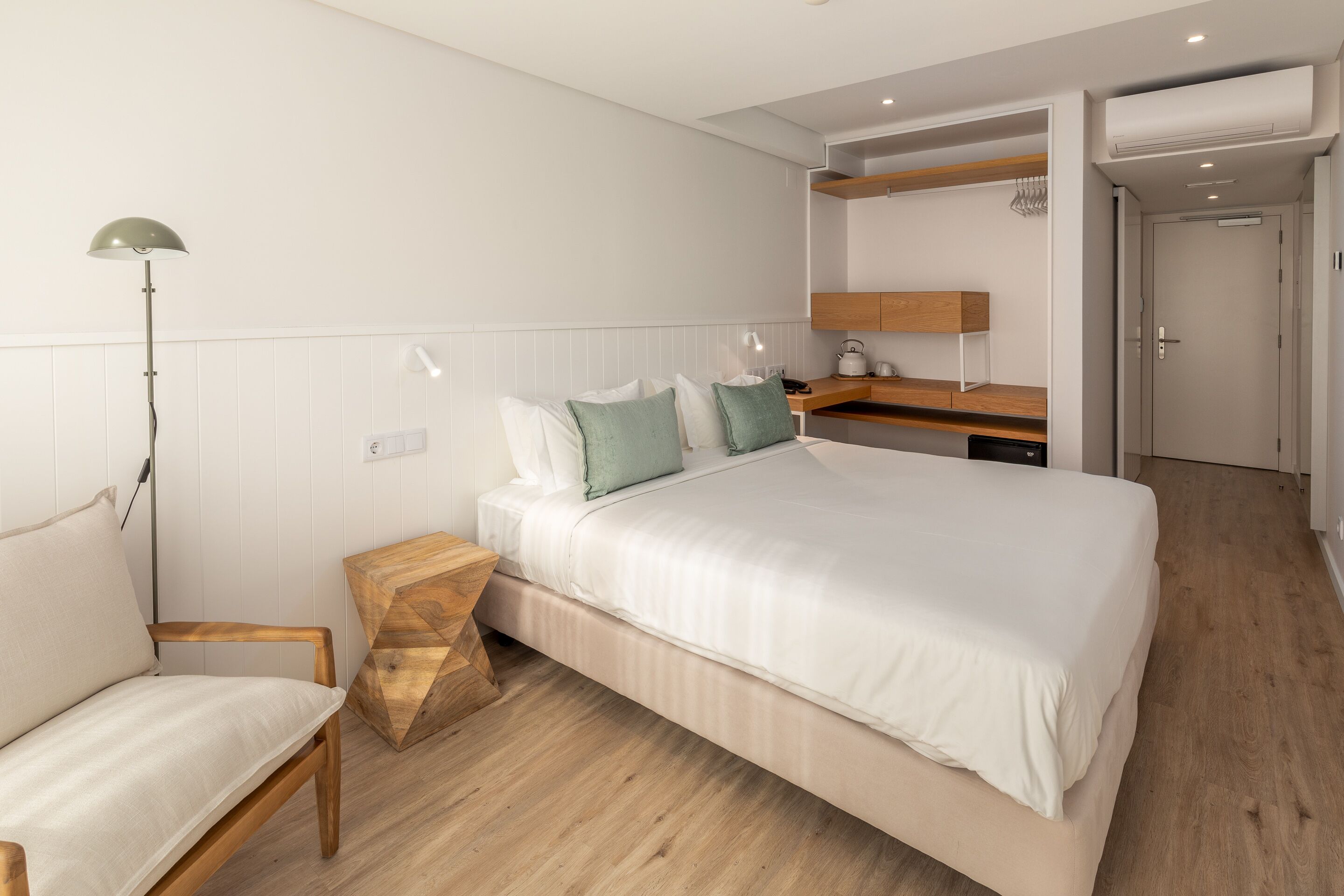 A modern bedroom with a bed, bedside table, lamp, and a wooden nightstand.