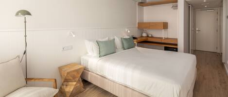 A modern bedroom with a bed, bedside table, lamp, and a wooden nightstand.