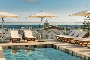 A rooftop pool area with lounge chairs and umbrellas, overlooking a coastal cityscape. - Pure Formosa Concept Hotel (Olhao)