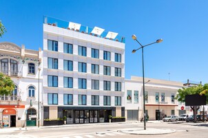 Un hotel de varios pisos con fachada moderna, amplias ventanas y una entrada destacada con puerta de cristal.