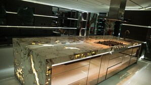 A modern kitchen with a marble countertop, stainless steel appliances, and a glass backsplash. - Stunning Golden Marble Suite Parque Lleras (Medellín)