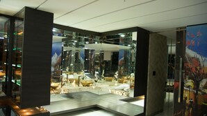 A modern interior with a reflective glass wall, a marble floor, and a central seating area with a white sofa and a small table. - Stunning Golden Marble Suite Parque Lleras (Medellín)
