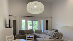 A spacious living area with a white dining table and chairs, a large beige sofa, and a hanging light fixture. - Sunset Limited: two blocks to the beach. Sleeps 2 (Bay St. Louis)