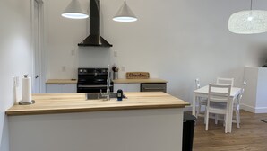 A modern kitchen with a central island, black stove, and pendant lights. - Sunset Limited: two blocks to the beach. Sleeps 2 (Bay St. Louis)