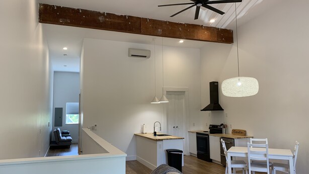 A modern kitchen with a dining area, a staircase, and a living room with a sofa. - Sunset Limited: two blocks to the beach. Sleeps 2 (Bay St. Louis)