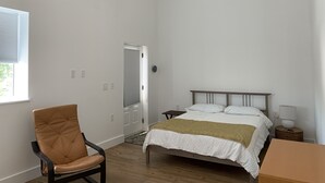 A bedroom with a bed, a chair, a bedside table, and a ceiling fan. - Sunset Limited: two blocks to the beach. Sleeps 2 (Bay St. Louis)