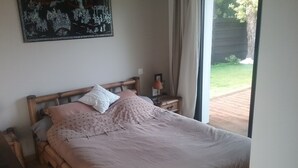 Un lit bien fait, avec une tête de lit en bois, une table de chevet sur laquelle se trouve une lampe, et un tableau encadré accroché au mur.