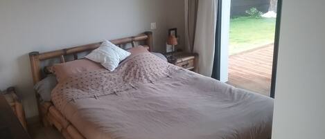 A neatly made bed with a wooden headboard, a bedside table with a lamp, and a framed picture on the wall.