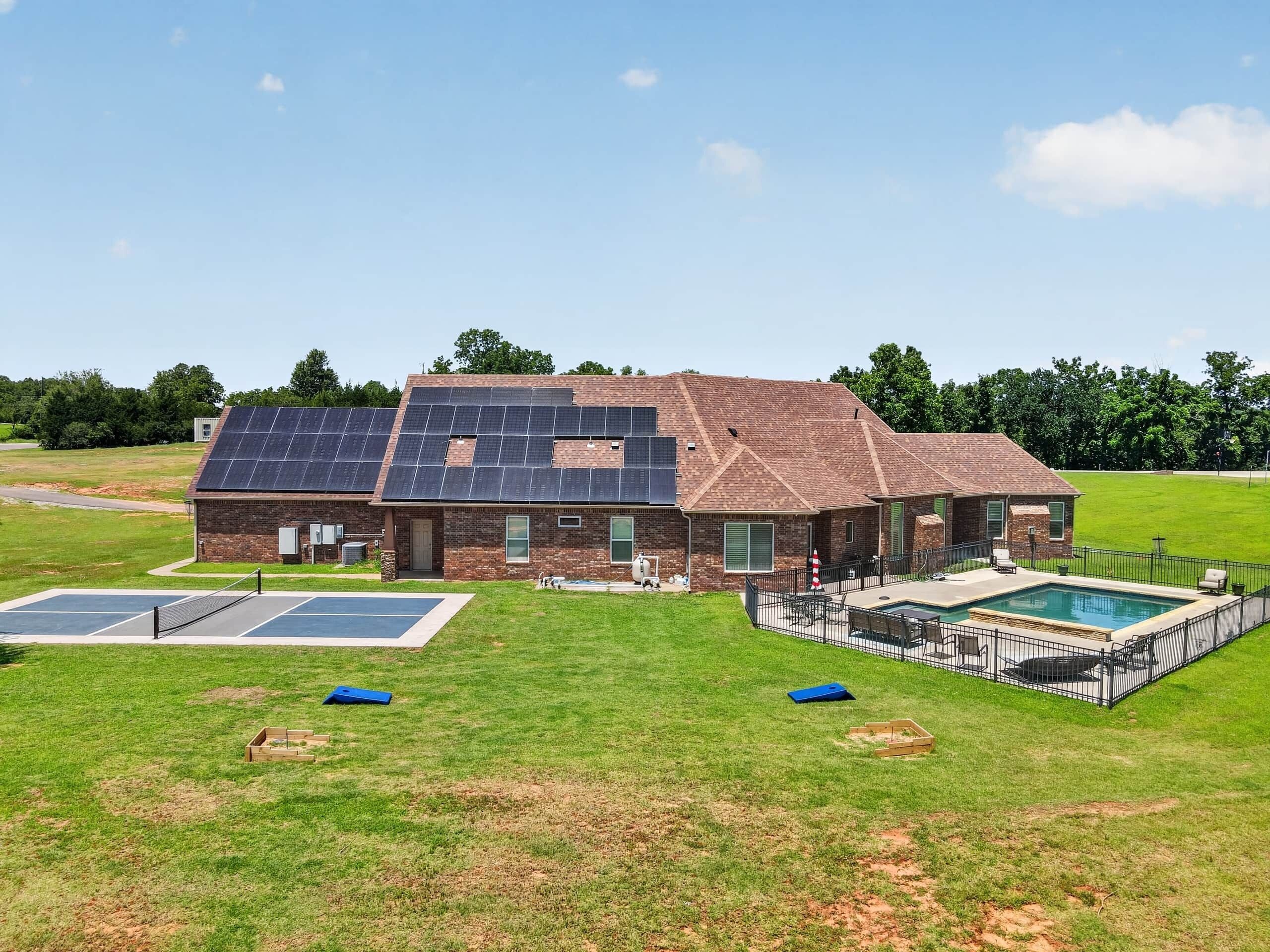 Una casa con paneles solares, piscina y cancha de baloncesto.