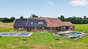 Una casa con paneles solares, piscina y cancha de baloncesto.