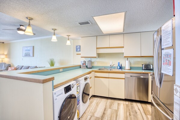 Una cocina moderna con lavadora y secadora integradas, electrodomésticos de acero inoxidable y encimera de madera.