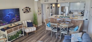 Una sala de estar moderna con televisor, zona de estar y cocina con mesa de comedor.