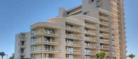 A multi-story hotel with balconies, a pool, and a fountain.