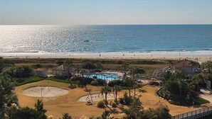 Un complex turístic a la costa amb piscina, accés a la platja i una vista despejada de l'oceà.