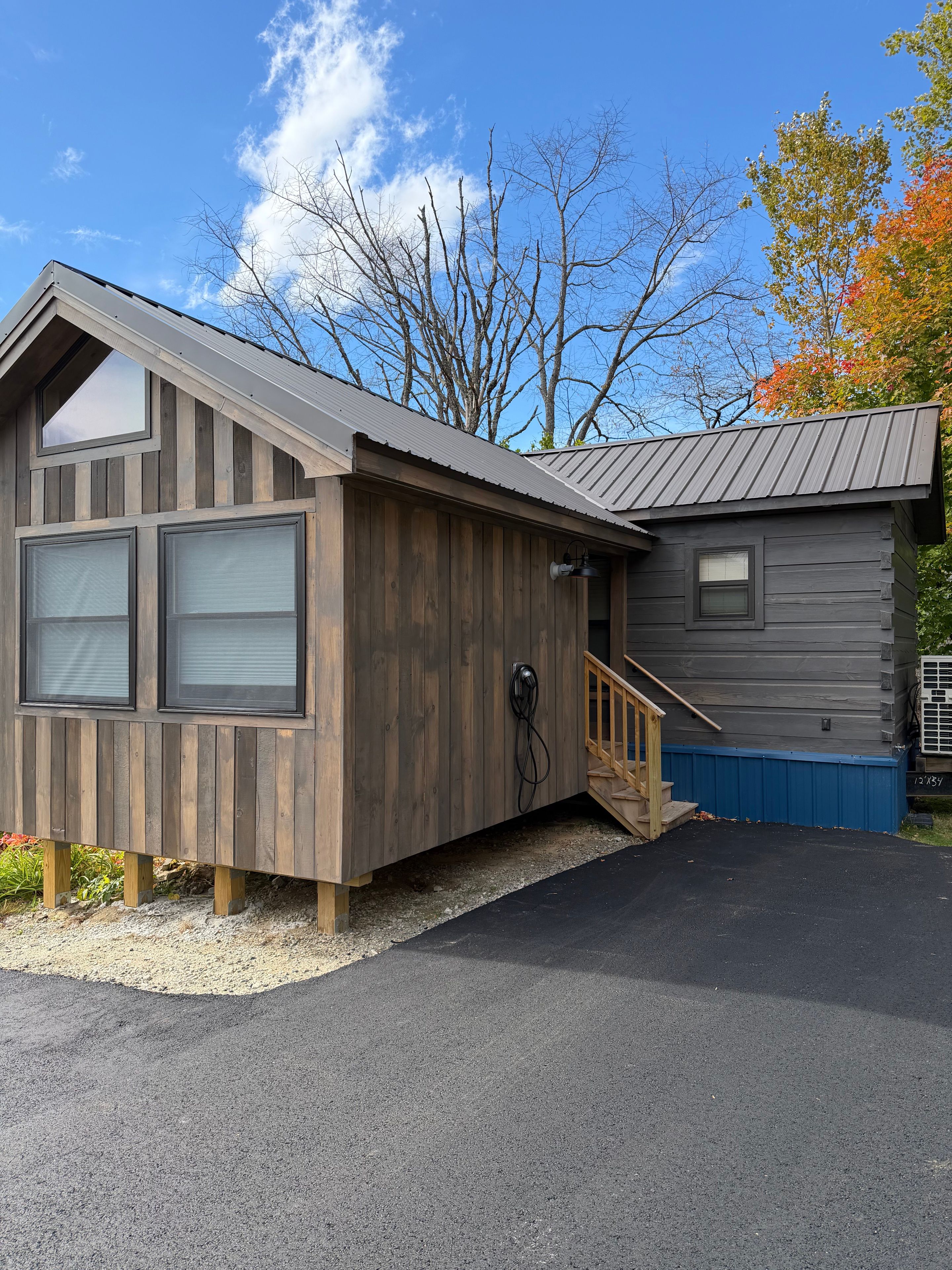 A two-story wooden cabin with a garage, a covered porch, and a small deck.