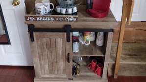 A coffee station with a sign stating "Life Begins with Coffee," a Keurig coffee maker, and various coffee cups and containers. - Betty Lou's Garden Guest Suite (Nashville)